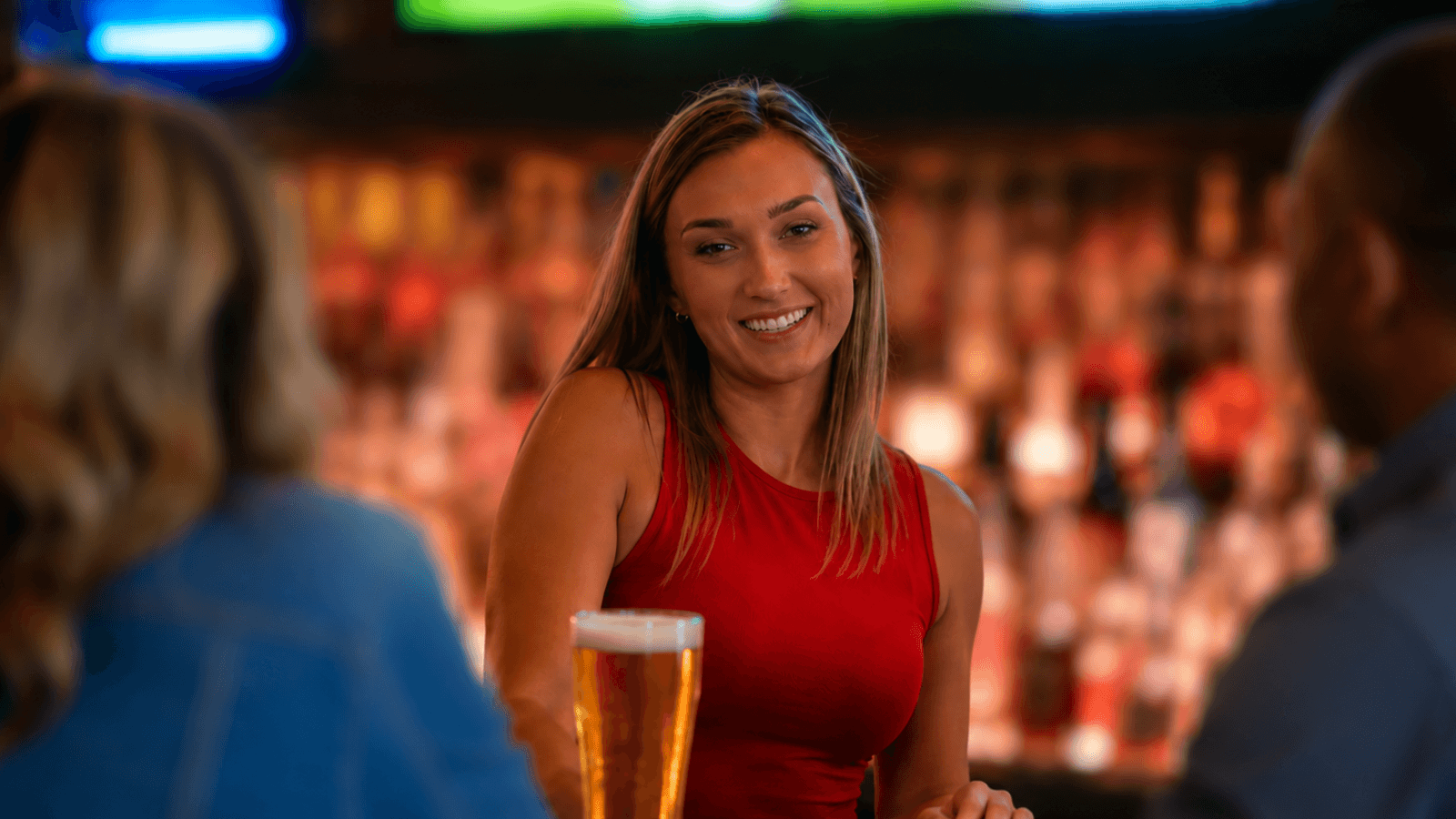 Bartender in red smiling at the bar and talking to guests